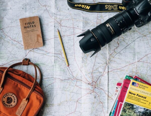 SLR camera, backpack, pencil, field notes book on paper map