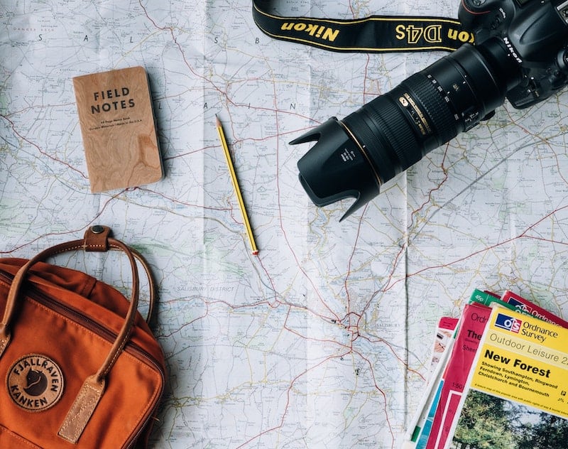 SLR camera, backpack, pencil, field notes book on paper map