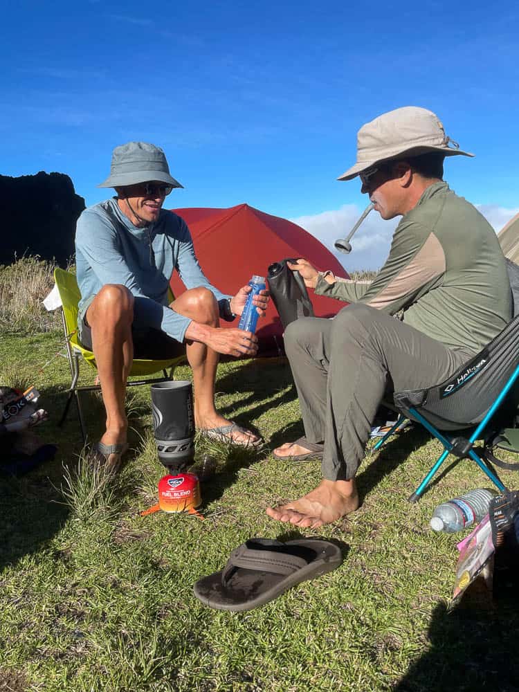 Two men sitting in camping chairs holding water bottles