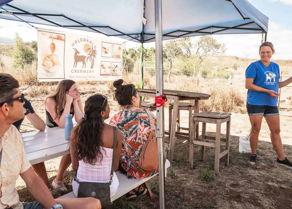 A group of five people under a tent at Haleakala Creamery, looking at tour guide Rebecca