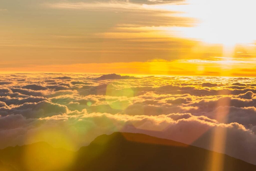 The sun flares above the clouds at Haleakala National Park