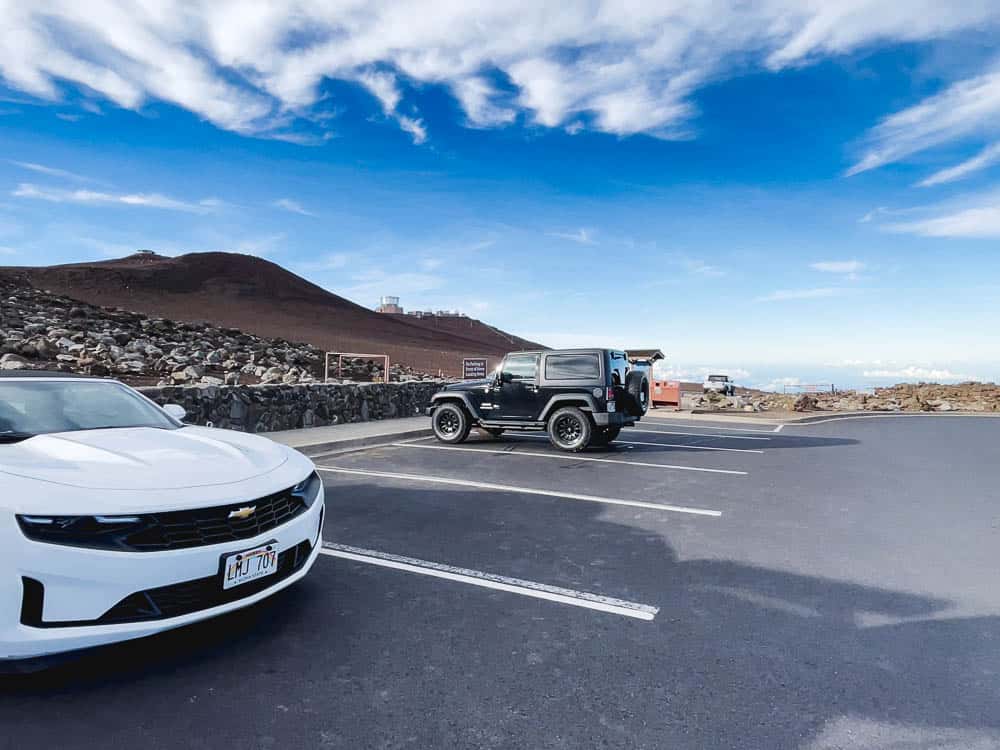 A black Jeep and white Chevrolet in the parking lot at the Haleakala National Park visitor center.