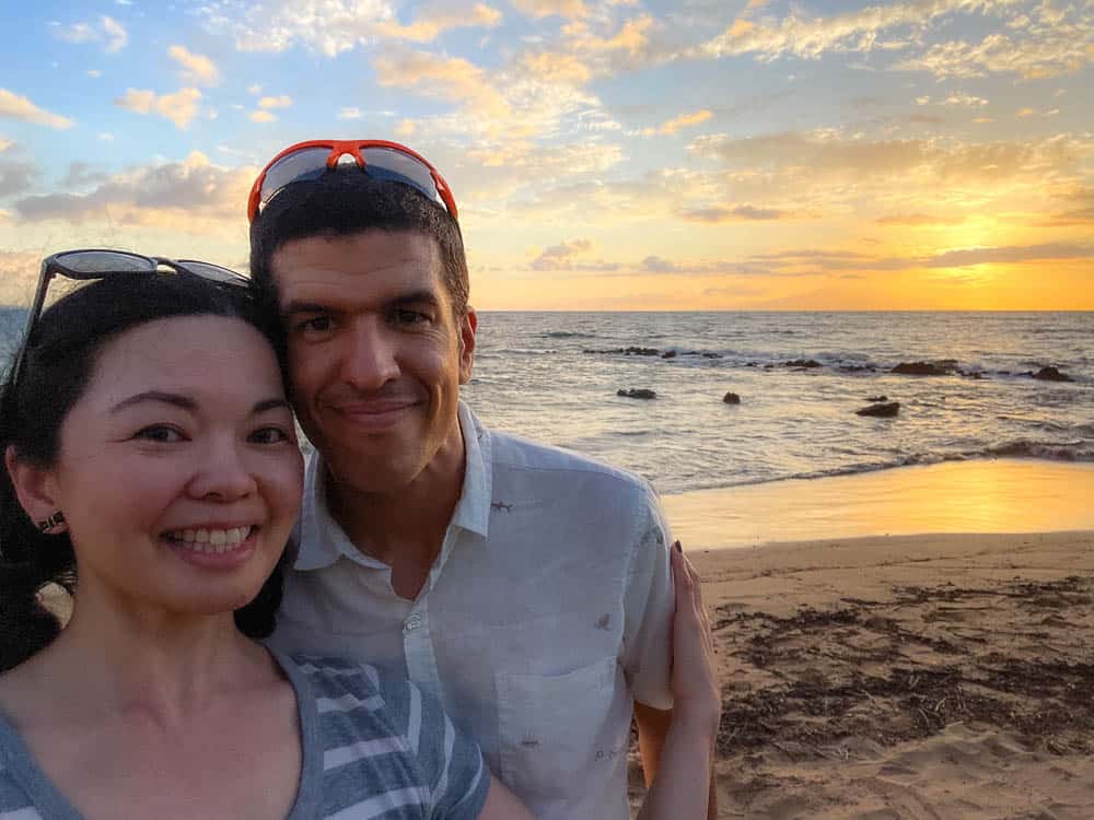 Woman and man posing in front of a beach sunset