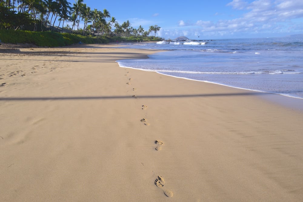 Footprints in the sand on Keawakapu Beach leading to the ocean water