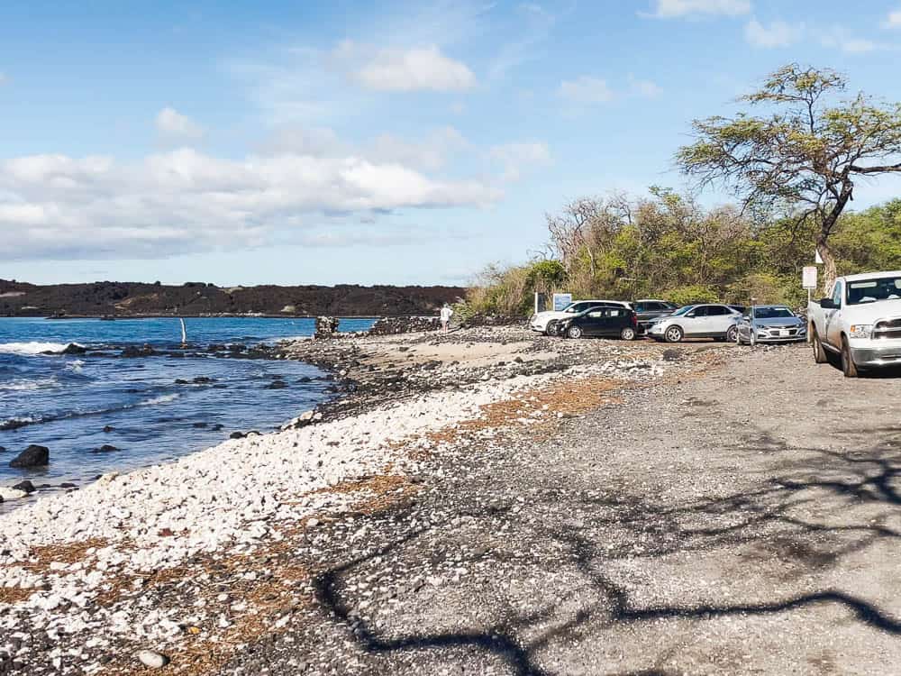 Cars parked on a gravel parking lot next to La Perouse Bay water in Maui Hawaii