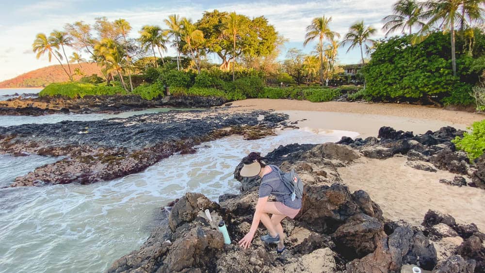 A woman stepping down from the rocky outcropping at Makena Cove, Maui