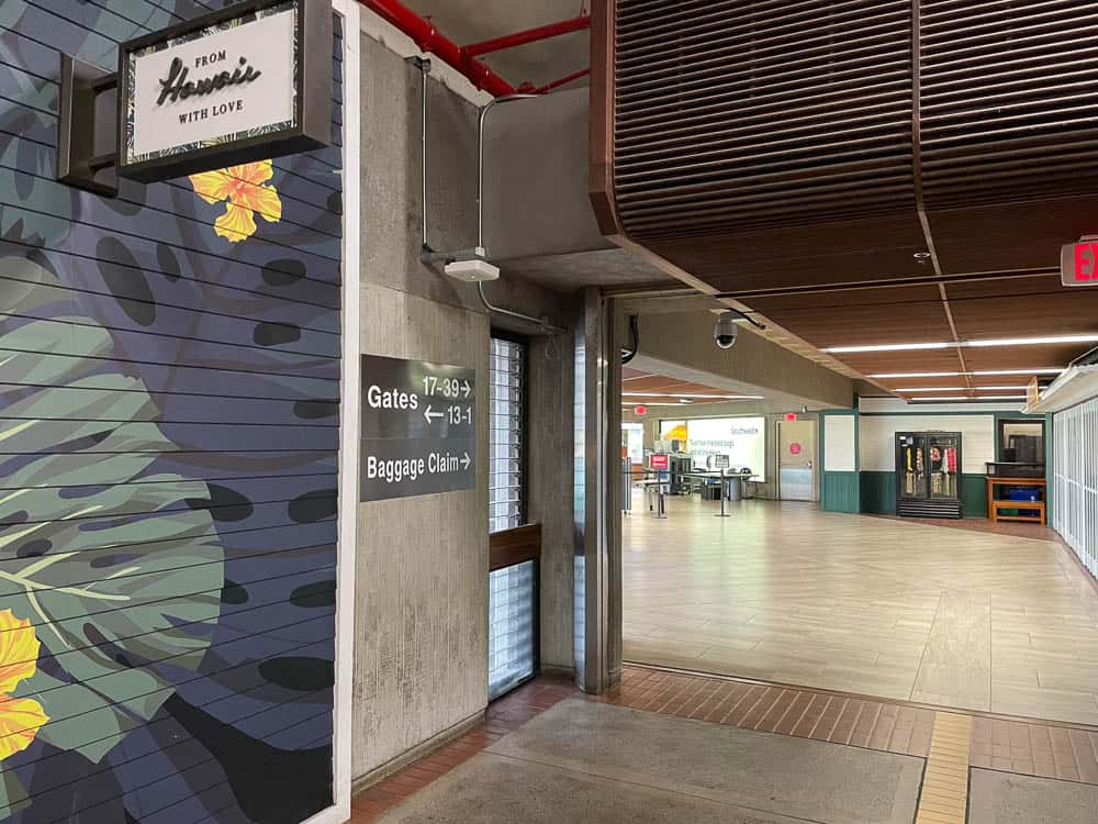 Directional wall signs pointing to airline gates and baggage claim at Maui's Kahului Airport (OGG)