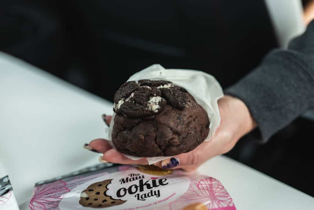 A hand holding a baseball-sized chocolate cookie.