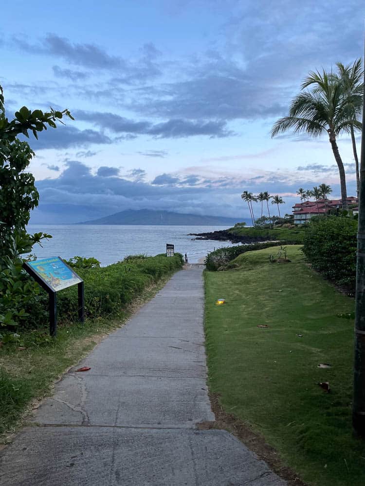A sidewalk leading to the beach in front of Wailea's Fairmont Kea Lani with West Maui across the ocean in the far distance.