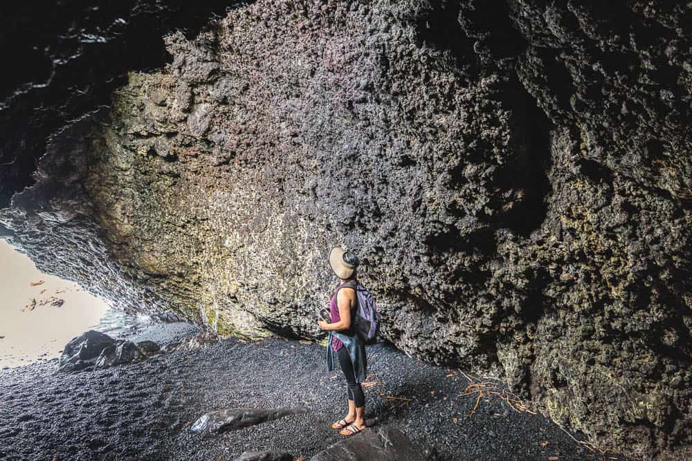 A woman stands in a lava cave at Waianapanapa State Park on Maui, Hawaii
