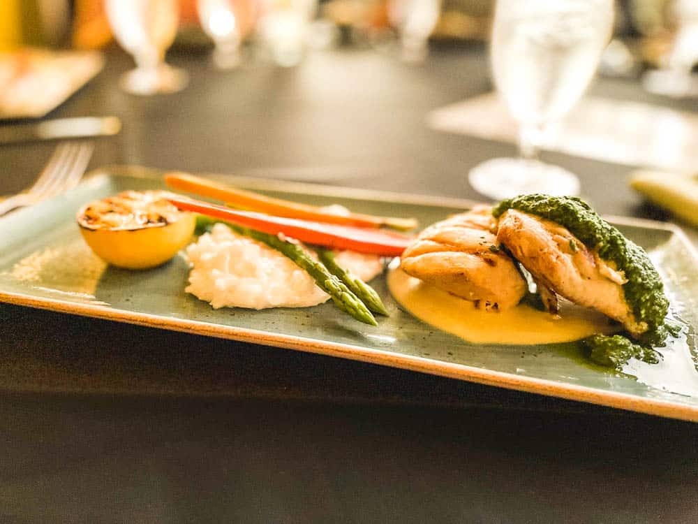 A green rectangular plate topped with a gourmet dish: half a lemon, carrots, asparagus, and fish at Ko in Wailea, Maui